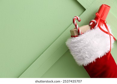 Christmas sock hanging with gift boxes and candy canes on green background - Powered by Shutterstock