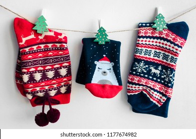 Christmas Socks For All Family Hanging On The Clothesline On White Background. Winter Holiday Concept.