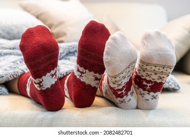 Christmas socks of family couple feet relaxing on couch having good holiday time together, enjoying resting at home in living room for winter Xmas boxing day and New Year celebration - Powered by Shutterstock