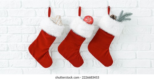 Christmas socks with gifts hanging on white brick wall - Powered by Shutterstock