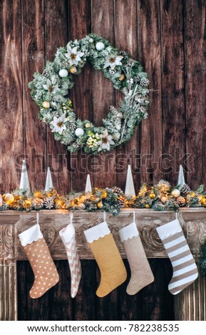 Christmas socks on decorated fireplace, background of a wooden wall with a green wreath