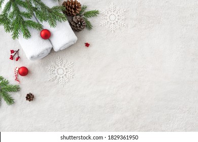Christmas Spa Concept and Winter Skin Care products, fir branches and snowflakes on white soft towel background, flat lay, copy space.  Seasonal beauty routine and body care concept.