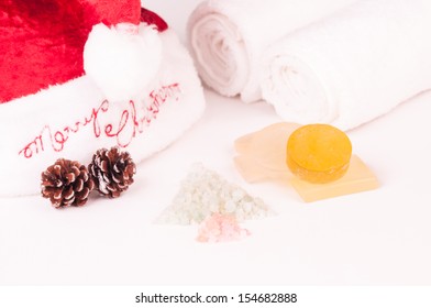Christmas spa getaway with christmas tree shaped bath salts, soaps, towels and santa hat on bed close up