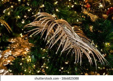 Christmas Sparkling Golden Luxury Decorations In Tropical Style On A Background Of A Christmas Tree With Festive Lights.