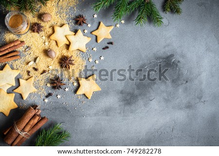Christmas spices, gingerbread cookies and baking ingredients on grey concrete background. Cinnamon, anise stars, nutmeg, cardamon, cloves, brown sugar for Christmas cookies.