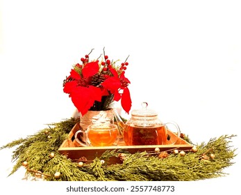 Christmas spirit. On a w2hite background in fir branches, a wooden tray with traditional Christmas flower, pine cones, a teapot and cup with green tea. - Powered by Shutterstock