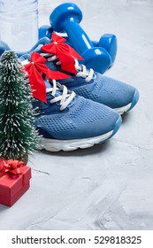 Christmas sport composition with sport shoes, dumbbells, 
red gift box, christmas tree and bottle of water on gray concrete 
background. Concept Ã?Â�hristmas special for healthy lifestyle and 
sport.