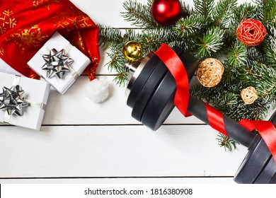 Christmas Sport Equipment: Dumbbells And Fir Branches, Gifts, Christmas Decorations On A Wooden White Background. Fitness, Sport Or Healthy Lifestyle Concept. New Year. Christmas.