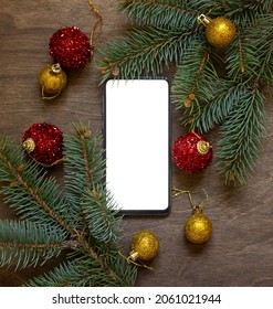 Christmas Spruce Branch And Phone With Red And Yellow Balls On Wooden Background.