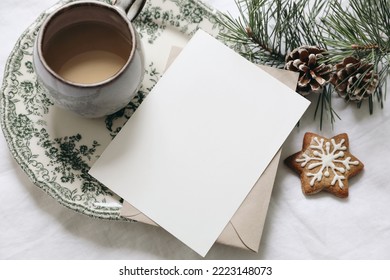 Christmas still life. Blank greeting card, invitation mockup.Gingerbread cookie, cup of coffee and pine tree branches. Floral green plate. White linen tablecloth with envelope. Winter festive flatlay. - Powered by Shutterstock