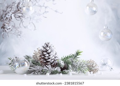 Christmas still life with snowy pine cones, baubles and  fir branches on light background. Winter or Christmas festive concept. - Powered by Shutterstock