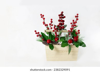 Christmas Still Life. Wooden basket with holly branches inside. White background. Horizontal. - Powered by Shutterstock