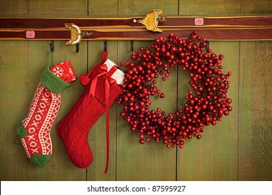 Christmas Stockings And Wreath Hanging On Rustic Wall