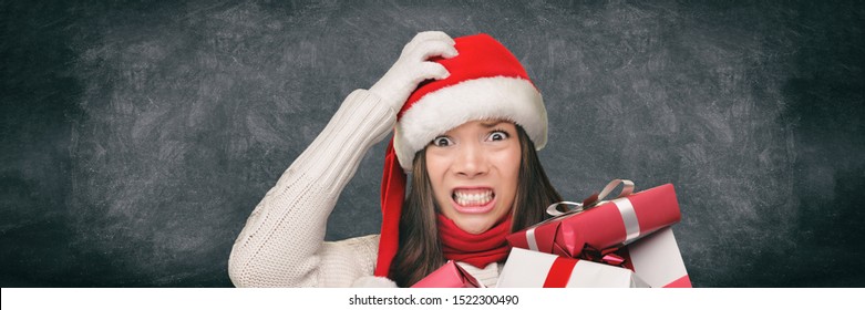 Christmas Stress Holiday Shopping Woman In Santa Hat Stressed Funny Expression On Black Blackboard Banner Panorama. Anxious Lady Shopper Late For Christmas Gifts Stressing About The Budget Spending.