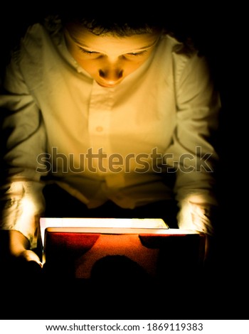 Similar – Boy reading with a flashlight