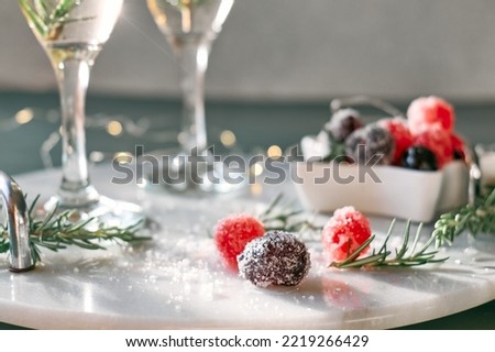 Christmas sweets near wine glasses with cocktail with sparkling wine, rosemary and cherry. Winter xmas and new year holidays champagne drink. selective focus.
