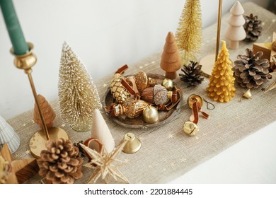 Christmas Table Decor. Stylish Christmas Golden Trees, Runner With Gold Stars, Shiny Baubles And Candles On Table. Modern Gold Christmas Decorations. Holiday Arrangement, Table Setting