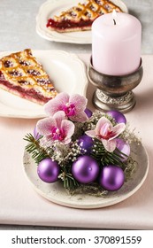 Christmas table decoration with violet balls, fir and orchid flowers.