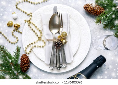 Christmas table place setting with christmas pine branches and plate, kine, fork and spoon on a light slate,stone or concrete background.Christmas holiday background.Top view.