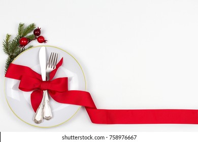 Christmas Table Place Setting With Plate, Cutlery, Pine Branches,  Ribbon And Red Berries. Winter Holidays And Festive Background. Christmas Eve Dinner, New Year Food Lunch. View From Above, Top