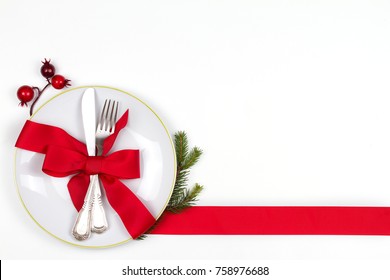 Christmas Table Place Setting With Plate, Cutlery, Pine Branches,  Ribbon And Red Berries. Winter Holidays And Festive Background. Christmas Eve Dinner, New Year Food Lunch. View From Above, Top