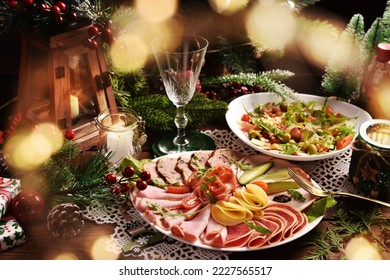 Christmas table with a platter of sliced ham, salami, cheese and cured meats and salad with vegetables, ham and arugula leaves - Powered by Shutterstock