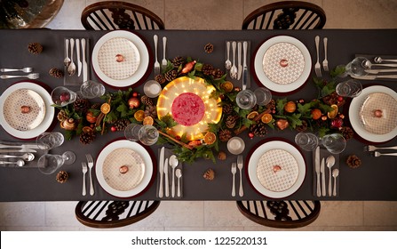 Christmas Table Setting With Baubles Arranged On Plates And Green And Red Table Decorations, Overhead View