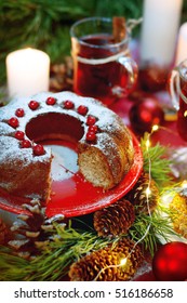 Christmas table setting. Bundt cake pudding sprinkled with sugar powder decorated with red currant and mulled wine.