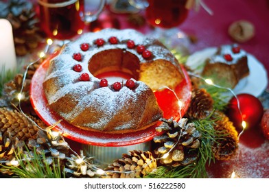 Christmas table setting. Bundt cake pudding sprinkled with sugar powder decorated with red currant and mulled wine.