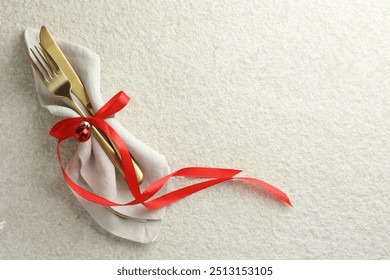 Christmas table setting. Cutlery, napkin, ribbon and bauble on light textured background, top view. Space for text - Powered by Shutterstock