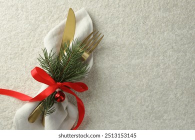 Christmas table setting. Cutlery, napkin, ribbon, fir branches and bauble on light textured background, top view. Space for text - Powered by Shutterstock