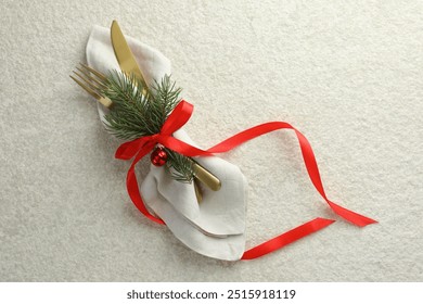 Christmas table setting. Cutlery, napkin, ribbon, fir branches and bauble on light textured background, top view - Powered by Shutterstock