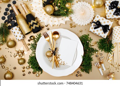 Christmas Table Setting With Empty Card Mockup For Your Text. Gold And Black Decoration With Fir-tree Branch. Flat Lay, Top View. 