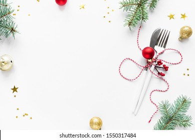 Christmas Table Setting with fir branch and red ornaments on white, flat lay, copy space. Christmas dinner, party design, concept - table setting with festive decoration.