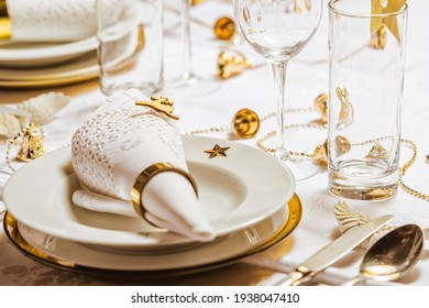Christmas table setting. White napkin with gold ring.