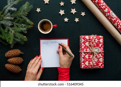 Christmas Table With Various Items. Woman's Hand Writing A Letter