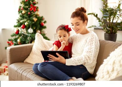 Christmas, Technology And Family Concept - Happy Mother And Little Daughter With Tablet Pc Computer At Home