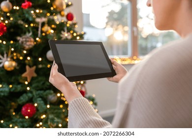 christmas, technology and winter holidays concept - close up of woman with tablet pc computer at home