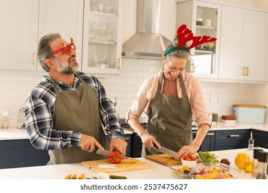 Christmas time, cooking in kitchen, mature couple wearing festive accessories at home. celebration, togetherness, happiness, season, decorative, elderly - Powered by Shutterstock