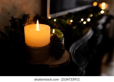 Christmas time, Glowing candle on mantel with pinecone and festive garland, creating warmth, at home. Candlelight, cozy, holiday, decoration, winter, ambiance - Powered by Shutterstock