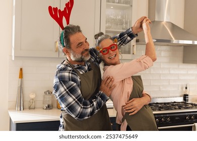 Christmas time, Joyful mature couple dancing in kitchen wearing festive holiday accessories, at home. Celebration, happiness, togetherness, lifestyle, home, domestic - Powered by Shutterstock