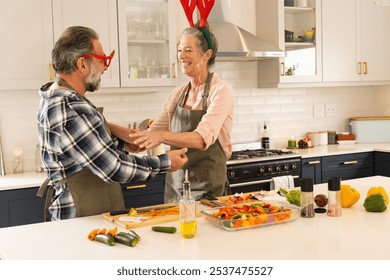 Christmas time, Mature couple in kitchen laughing and preparing festive meal together, at home. Cooking, domestic life, culinary, family, togetherness, bonding - Powered by Shutterstock