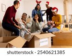 Christmas time, young multiracial friends laughing while sorting donations at home. celebration, charity, togetherness, giving, volunteering, happiness