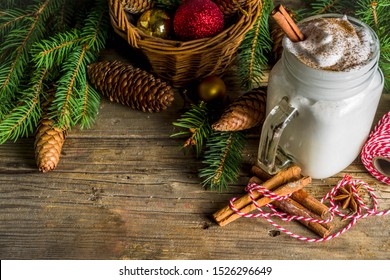 Christmas Tom and Jerry cocktail, whipped cream eggnog with spices, dairy milk beverage, with christmas decorations, rustic wooden background copy space
