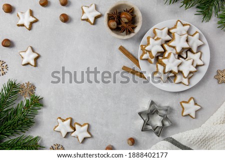 Christmas traditional German cookies, cinnamon stars with hazelnuts, decoration and tree branches on a light concrete background. Top view. Copy space.