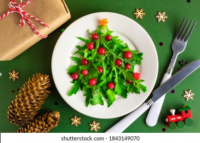 The Christmas tree arugula salad on white plate with knife and fork on green background. Flat lay. Vegetarian concept - Powered by Shutterstock