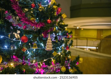 Christmas tree with balls, glowing garland and tinsel on the background of blur modern hotel building at night. Christmas holiday celebration. - Powered by Shutterstock