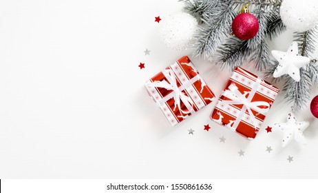 Christmas tree branch with balls and gifts on white background with copy space. Flat lay, top view. Winter holidays postcard template, Xmas banner mockup, New year greeting card - Shutterstock ID 1550861636