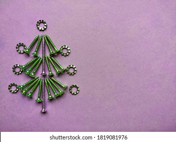 Christmas tree built of construction screws on a lilac background.