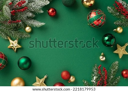 Christmas tree decorations concept. Top view photo of red gold green baubles star ornaments mistletoe berries and pine branches in hoarfrost on isolated green background with copyspace in the middle